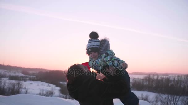 Una niña con un niño jugando en el parque de invierno.Camina al aire libre. Puesta de sol — Vídeos de Stock
