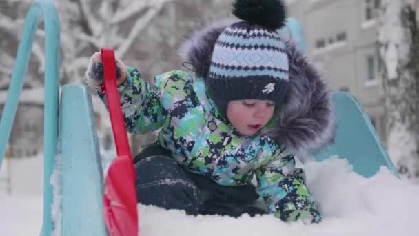 Ein kleines Kind, das im Winterpark mit Schnee spielt. sonniger Wintertag. Spiel und Spaß an der frischen Luft. — Stockvideo