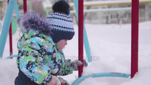 Egy kisgyermek játszik a hó a téli Park. Napos tél nap. Szórakozás és játékok a friss levegő. — Stock videók