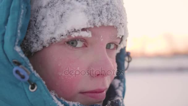 Ein Teenager im Winterpark lächelt in Großaufnahme. die Zeit des Sonnenuntergangs. Spaziergänge im Freien. ein gesunder Lebensstil — Stockvideo