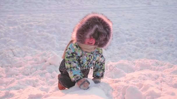 Un niño pequeño está jugando en el parque de invierno. Un día soleado de invierno. Diversión y juegos al aire libre . — Vídeos de Stock