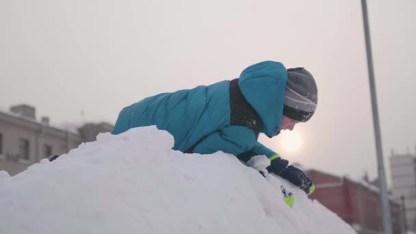 Tiener spelen op een besneeuwde berg. Uitzicht vanaf de top naar beneden. Zonnige frosty dag. Pret en spelen in de frisse lucht. — Stockvideo