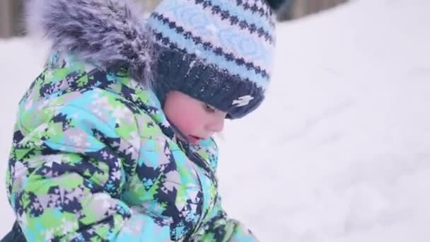 Маленька дитина грає на снігу. Сонячний зимовий день. Веселощі та ігри на свіжому повітрі . — стокове відео