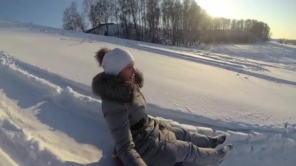 雪に覆われた丘の上に乗って幸せな女の子。スローモーション。雪に覆われた冬の風景。屋外スポーツ — ストック動画