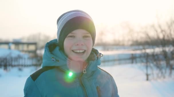 Un adolescente en el parque de invierno sonriendo de cerca. La hora del atardecer. Caminando al aire libre. Un estilo de vida saludable — Vídeos de Stock