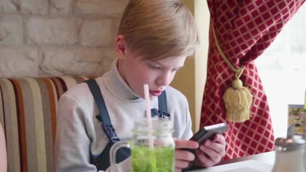 Bir kafede oturan ve bir akıllı telefon tutan genç. İş yemeği — Stok video