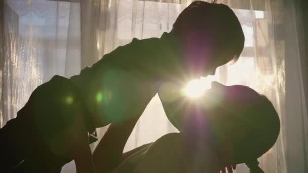 Madre che tiene un bambino piccolo per le mani. I raggi del sole attraverso la finestra. Le risate e la gioia del bambino . — Video Stock