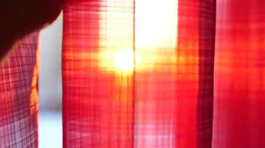 Kız kırmızı perdeler açılır ve elleri ile güneş ışınları ile oynadı. El portre