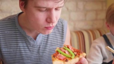 Adam alır ve peynir, jambon, domates ve otlar ile taze pişmiş pizza yiyor. İtalyan mutfağı