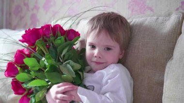 Büyük bir buket kırmızı gül tutan mutlu bebek. Anneler doğum günü için bir hediye