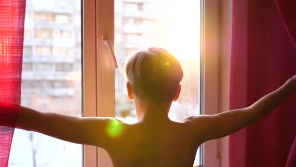 El tipo viene temprano a la ventana, abre las cortinas. Los rayos del sol pasan a través del vidrio . — Vídeo de stock