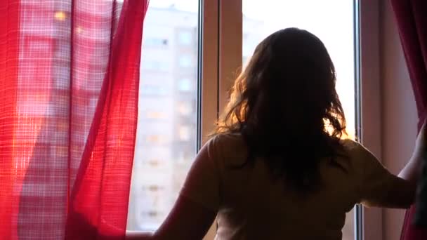 Felices parejas jóvenes enamoradas vienen a la ventana. El tipo gentilmente abraza a la chica y la besa. Los rayos del sol pasan por la ventana, iluminando la habitación . — Vídeos de Stock