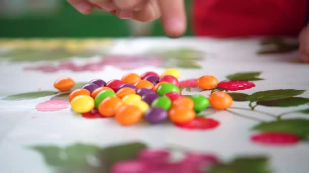 Kleine bunte Bonbons. Kinderhände nehmen Bonbons vom Tisch. Hände aus nächster Nähe — Stockvideo