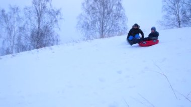 mutlu aile rides ve karlı roads.slow hareket üzerinde gülümseyen snowtube. kar kış manzara. açık havada spor