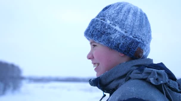 Подросток в зимнем парке, лицо крупным планом. Время заката. Гуляет на свежем воздухе. Здоровый образ жизни — стоковое видео