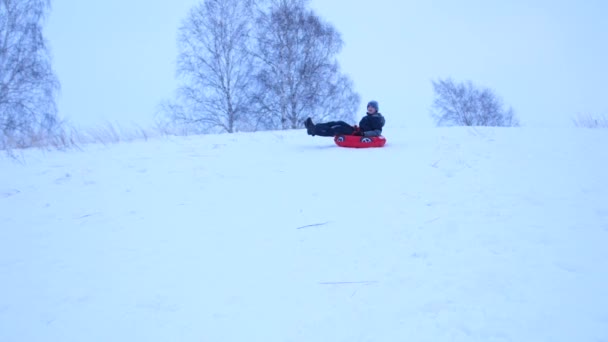 Guy rijden van een besneeuwde berg. Slow-motion. Besneeuwde winterlandschap. Outdoor sporten — Stockvideo