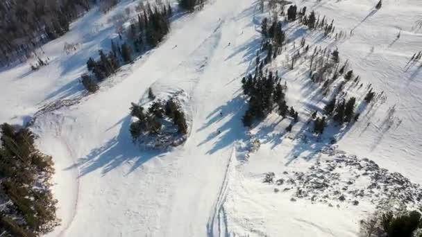 滑雪坡度。 滑雪者和滑雪者沿着跑道滑行. 滑雪者滑向宽阔的滑雪场时的空中摄影 — 图库视频影像