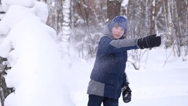 Ett barn leker utomhus på vintern, kastar snö. Aktiva utomhussporter. — Stockvideo