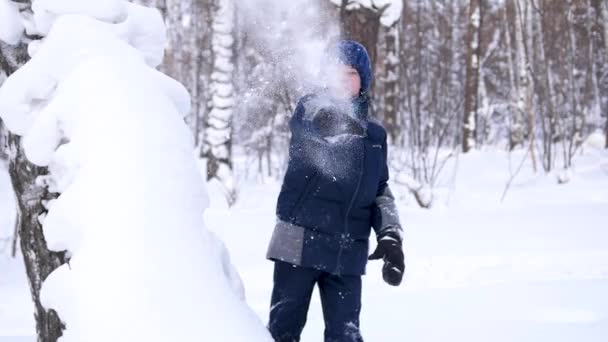 Dziecko bawi się zimą na świeżym powietrzu, rzuca śniegiem. Aktywne sporty zewnętrzne. — Wideo stockowe