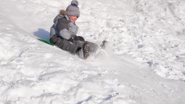 一个孩子骑在雪山上玩耍.慢动作冬天的雪景。户外运动 — 图库视频影像