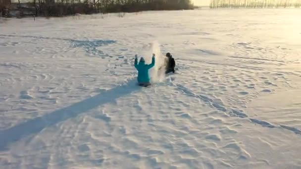 Dziewczyna i chłopiec rzucają na siebie śniegiem i cieszą się nim w zimowym parku. Zimowe spacery po parku. Śmiech i radość rodziny. — Wideo stockowe