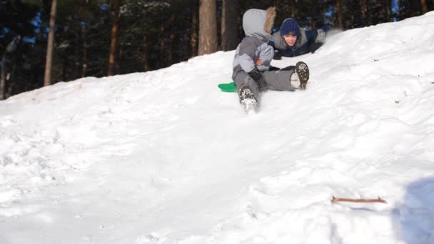 Children ride on a snowy mountain. Slow motion. Snowy winter landscape. Outdoor sports — Stockvideo