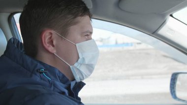 Adam araba kullanıyor. Yüzündeki tıbbi maske. İnsanlar koronavirüse karşı ekstra koruma kullanıyor..
