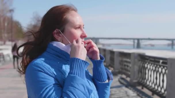 Het meisje draagt een beschermend masker op straat. Preventie en bescherming van de gezondheid en de veiligheid van het leven. Coronavirus N1H1, covid-19, pandemie in de wereld. — Stockvideo