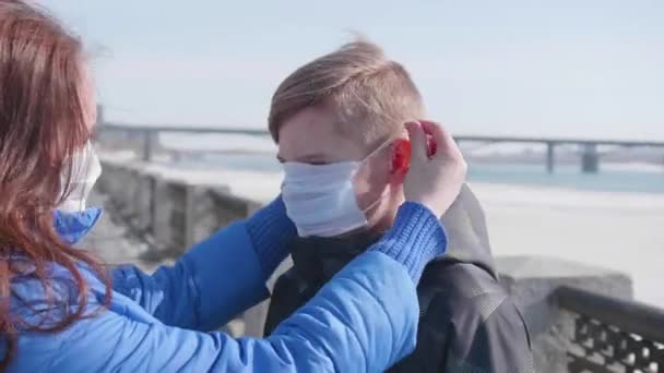 Het meisje draagt een beschermend masker op haar kind. Preventie en bescherming van de gezondheid en de veiligheid van het leven. Coronavirus N1H1, covid-19, pandemie in de wereld. — Stockvideo