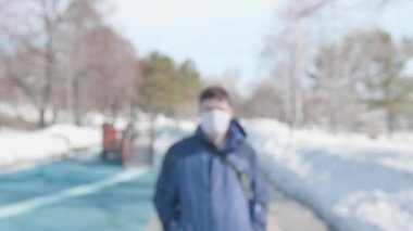 Adam sokakta koruyucu bir maskeyle dolaşıyor. Sağlık ve can güvenliğinin önlenmesi ve korunması.