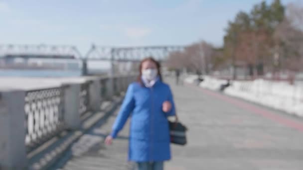 Een meisje loopt in een beschermend masker op de rivier. Preventie en bescherming van de gezondheid en de veiligheid van het leven. — Stockvideo