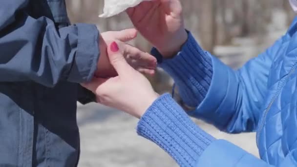 Девушка вытирает детям руки антибактериальной салфеткой на улице. Профилактика и защита здоровья и безопасности жизни . — стоковое видео