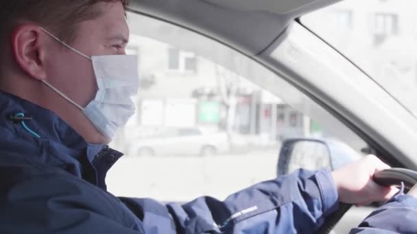 Killen kör bilen. Medicinsk mask i ansiktet. Människor använder extra skydd mot bakterier. — Stockvideo