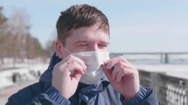 De man doet zijn beschermend masker af op straat. Preventie en bescherming van de gezondheid en de veiligheid van het leven. — Stockvideo