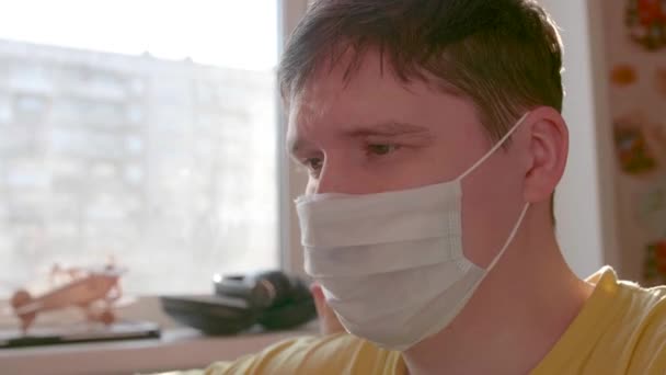O tipo com uma máscara protectora fica em casa em autoisolamento. Prevenção e protecção da saúde e da segurança da vida . — Vídeo de Stock