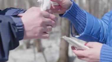 İnsanlar sokakta ellerini antibakteriyel mendille silerler. Sağlık ve can güvenliğinin önlenmesi ve korunması.