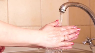 Kız, mikropların veya virüslerin kirli ellerden geçmesini önlemek için yürüyüşe çıktıktan sonra ellerini sıcak su ve sabunla yıkıyor. Sağlık ve can güvenliğinin önlenmesi ve korunması.