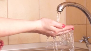 Kız, mikropların veya virüslerin kirli ellerden geçmesini önlemek için yürüyüşe çıktıktan sonra ellerini sıcak su ve sabunla yıkıyor. Sağlık ve can güvenliğinin önlenmesi ve korunması.
