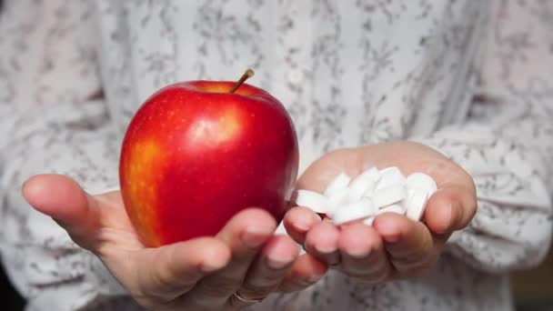 Το κορίτσι γιατρός κρατά ένα χάπι στο ένα χέρι και ένα μήλο στο άλλο. Παρέχοντας μια επιλογή υπέρ της σωστής διατροφής και των βιταμινών — Αρχείο Βίντεο