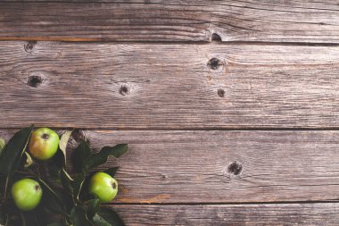Ahşap arka plan sayfasının sol köşesindeki yaprakları ile elma
