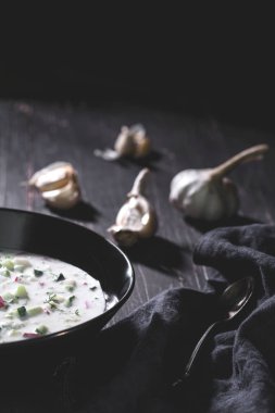 Siyah, ahşap masa kaşık ile siyah kapta sarımsak çorbası