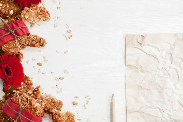 Gesunde vegane Haferkekse in rotem Papier auf dem weißen Holztisch — Stockfoto