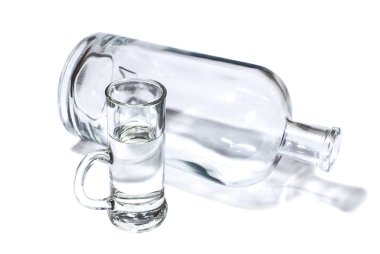 Şişe ve küçük bardak şeffaf güçlü içki ile dolu