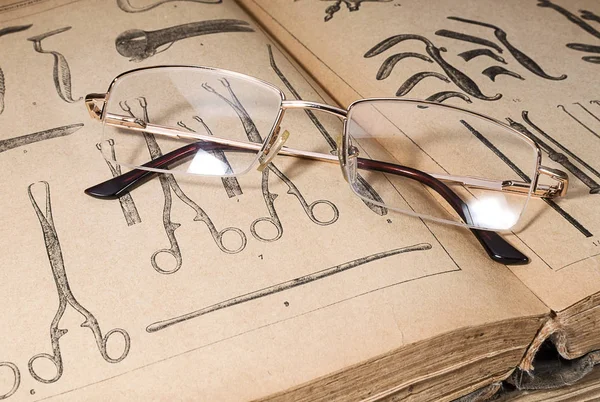Gold-rimmed eyeglasses on an old medical book