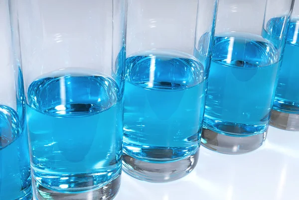 Rij glazen gevuld met blauwe vloeistof — Stockfoto