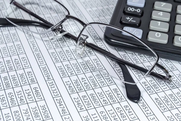 Eyeglasses and calculator on paper with numbers — Stock Photo, Image