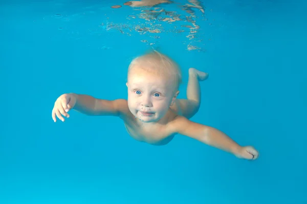 10 months infant boy learning to swim underwater in waterbaby class in the pool