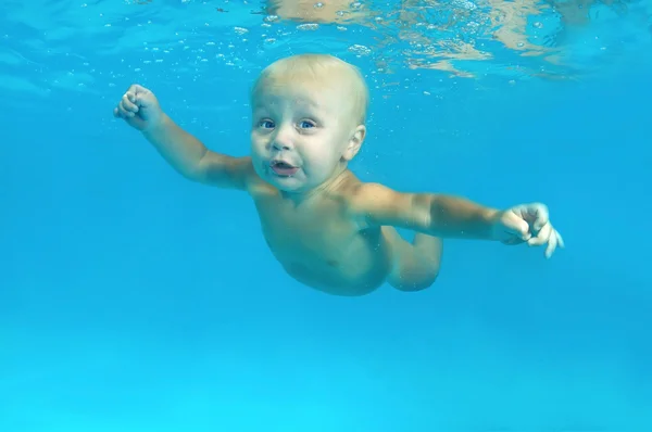 10 months infant boy learning to swim underwater in waterbaby class in the pool