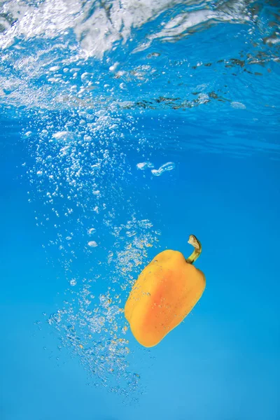 Bell pepper splashing in blue water
