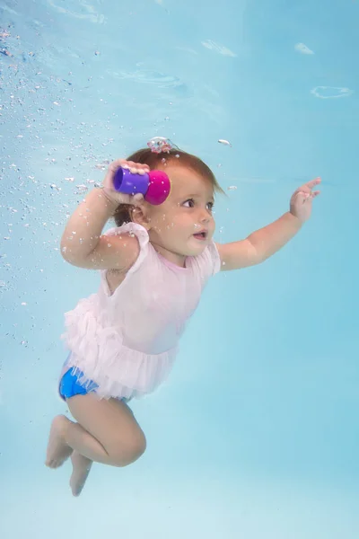 little girl learns to swim underwater in the pool